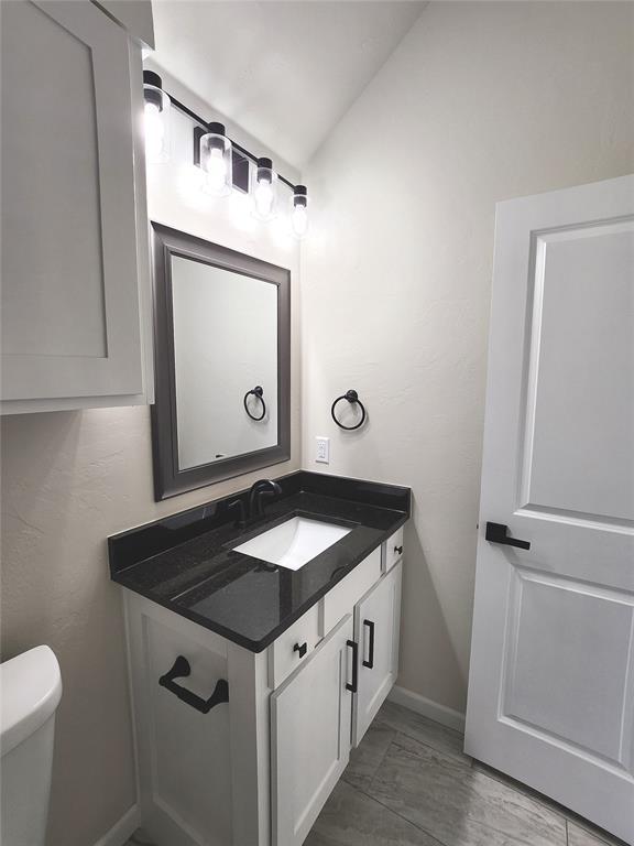 11613 NW 103rd St, Yukon, OK 73099 - bathroom with vanity, toilet, baseboards, and lofted ceiling