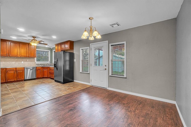 1724 N Lee St, Altus, OK 73521 - kitchen with tasteful backsplash, visible vents, black fridge, brown cabinetry, and stainless steel dishwasher