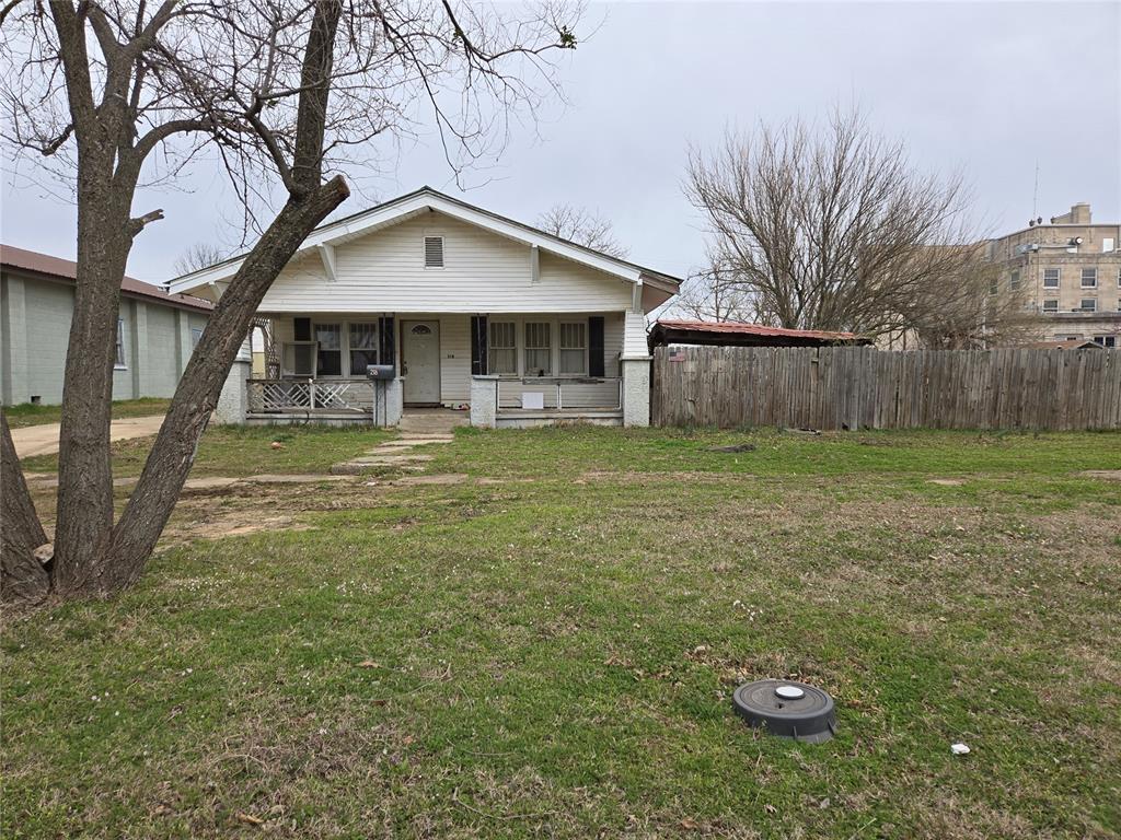 bungalow-style house featuring a front yard, fence, and covered porch