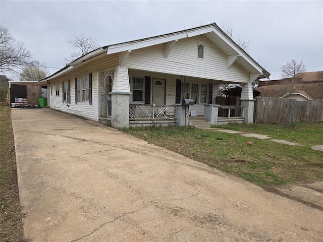 bungalow-style home with a porch, concrete driveway, and fence