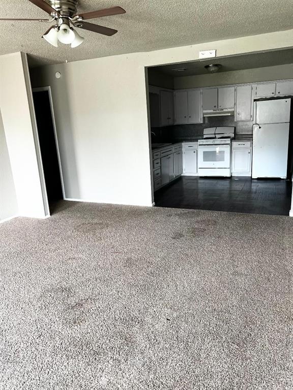 2513 N Nottingham Way, Moore, OK 73160 - kitchen with white appliances, dark countertops, a textured ceiling, ceiling fan, and open floor plan