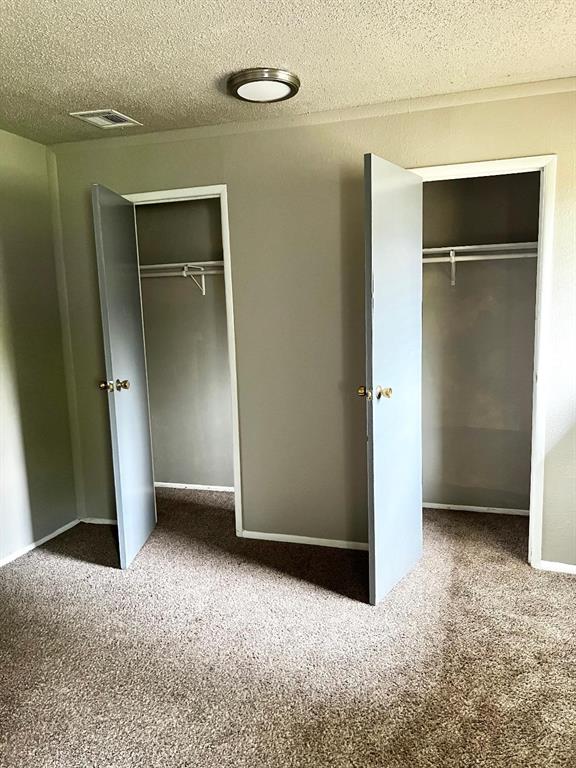2513 N Nottingham Way, Moore, OK 73160 - unfurnished bedroom with carpet floors, a textured ceiling, and a closet