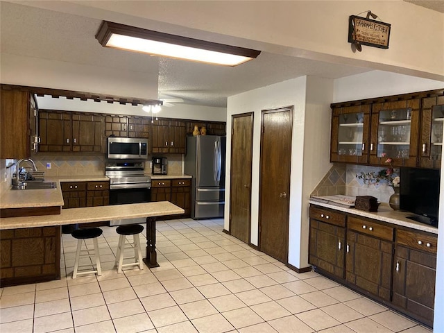 2416 SW 92nd St, Oklahoma City, OK 73159 - kitchen with light countertops, tasteful backsplash, a sink, dark brown cabinets, and appliances with stainless steel finishes