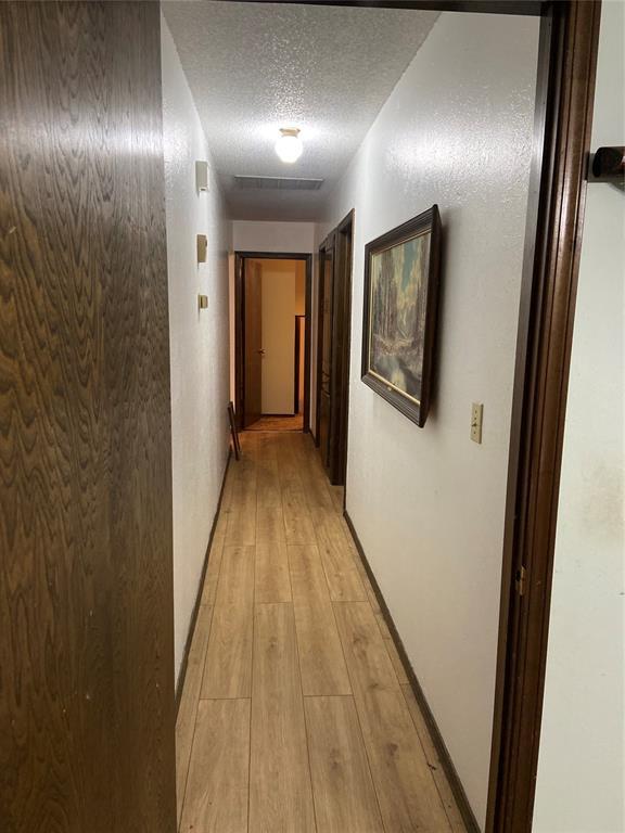 2416 SW 92nd St, Oklahoma City, OK 73159 - hallway featuring a textured ceiling and light wood-style flooring
