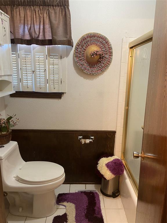 2416 SW 92nd St, Oklahoma City, OK 73159 - bathroom with tile patterned floors, bath / shower combo with glass door, and toilet