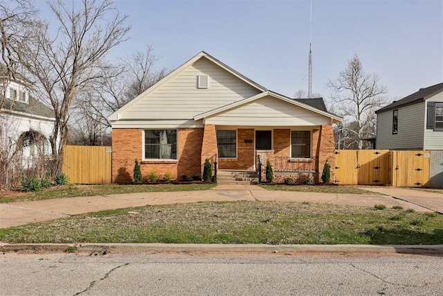 1721 NW 35th St, Oklahoma City, OK 73118 - bungalow-style home featuring fence, brick siding, covered porch, and a gate