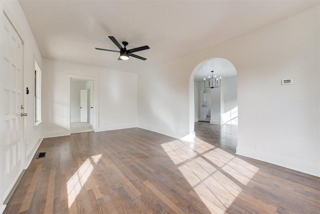 1721 NW 35th St, Oklahoma City, OK 73118 - empty room featuring dark wood finished floors, visible vents, ceiling fan with notable chandelier, and arched walkways
