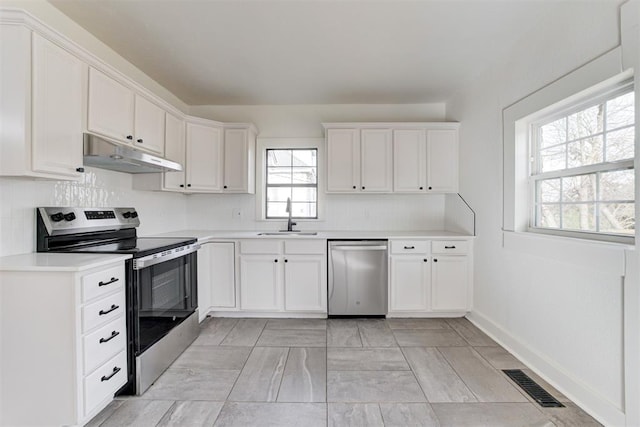 1721 NW 35th St, Oklahoma City, OK 73118 - kitchen with visible vents, under cabinet range hood, a sink, stainless steel appliances, and white cabinets
