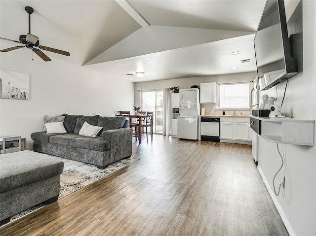 1415 NW 98th St, Oklahoma City, OK 73114 - living area with vaulted ceiling with beams, baseboards, stacked washing maching and dryer, light wood-style floors, and a ceiling fan