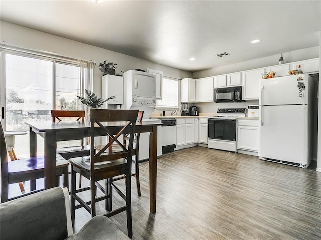 1415 NW 98th St, Oklahoma City, OK 73114 - kitchen with white appliances, wood finished floors, visible vents, white cabinets, and stacked washer / dryer