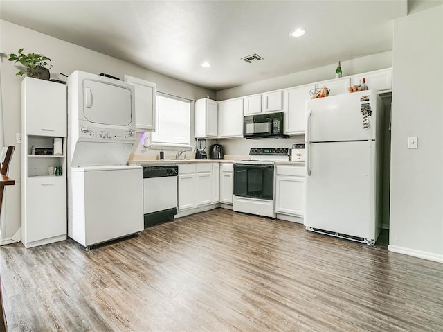 1415 NW 98th St, Oklahoma City, OK 73114 - kitchen with stacked washer / dryer, visible vents, light wood-style flooring, white appliances, and white cabinetry