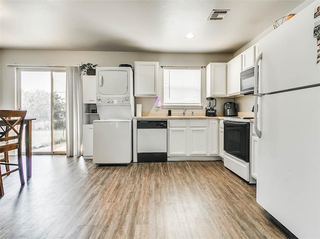 1415 NW 98th St, Oklahoma City, OK 73114 - kitchen with white appliances, visible vents, light wood-style flooring, white cabinetry, and stacked washer / dryer