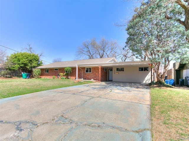 single story home featuring brick siding, an attached carport, concrete driveway, and a front yard