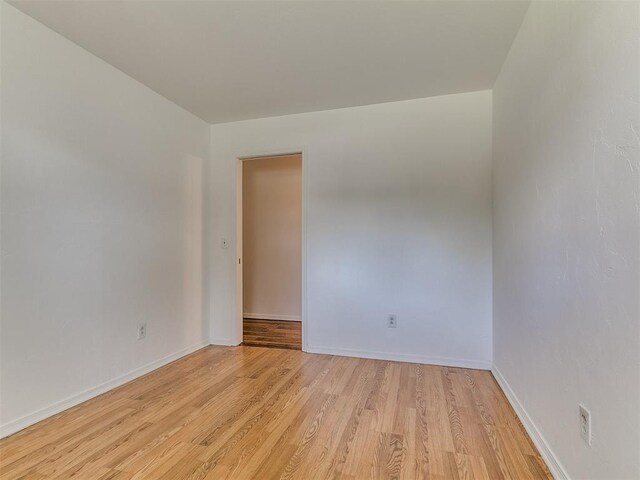 empty room featuring light wood-type flooring and baseboards