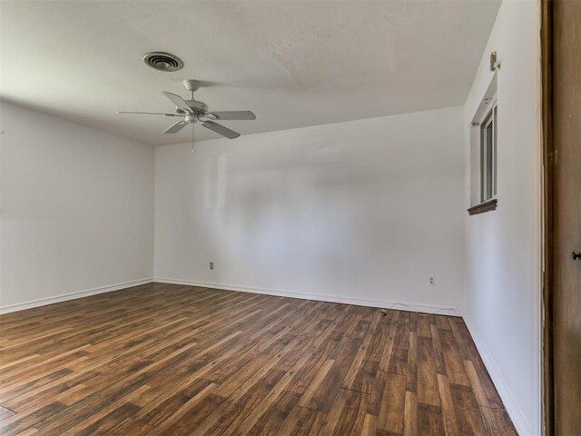 empty room with dark wood-type flooring, baseboards, visible vents, and ceiling fan