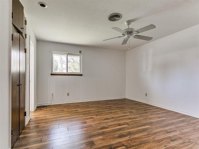 unfurnished bedroom with ceiling fan, visible vents, baseboards, and dark wood finished floors