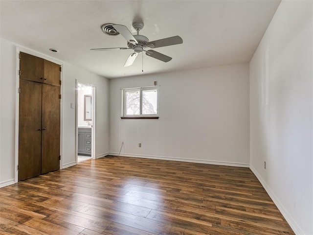 unfurnished bedroom featuring connected bathroom, a ceiling fan, baseboards, and wood-type flooring