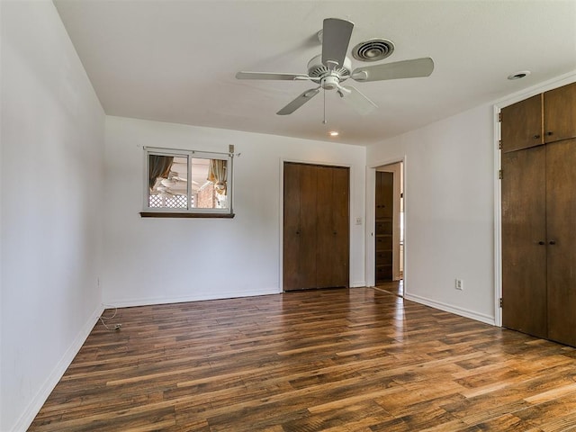 unfurnished bedroom featuring a ceiling fan, wood finished floors, visible vents, baseboards, and a closet
