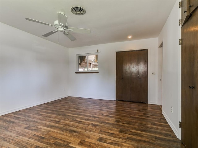 unfurnished bedroom featuring dark wood finished floors, baseboards, visible vents, and a closet