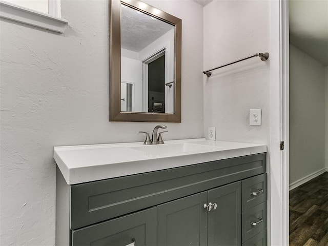 bathroom featuring vanity, a textured wall, and wood finished floors