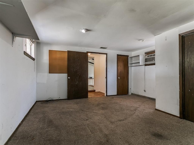 unfurnished bedroom with visible vents, ensuite bathroom, a wall mounted AC, and carpet floors