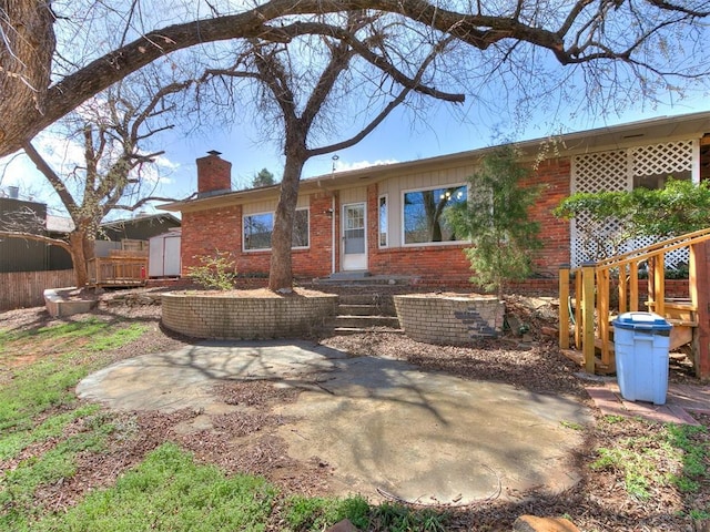 rear view of house featuring a storage shed, an outdoor structure, brick siding, and a chimney