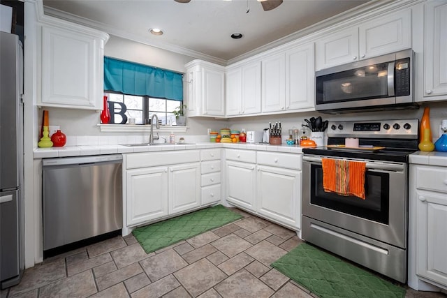 4505 N Peniel Ave, Bethany, OK 73008 - kitchen featuring appliances with stainless steel finishes, tile countertops, white cabinetry, ornamental molding, and stone finish floors
