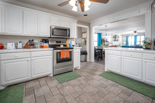 4505 N Peniel Ave, Bethany, OK 73008 - kitchen with appliances with stainless steel finishes, a ceiling fan, tile countertops, and ornamental molding