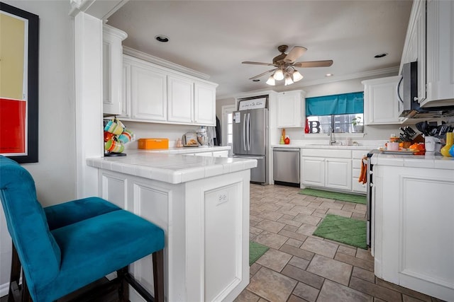 4505 N Peniel Ave, Bethany, OK 73008 - kitchen with appliances with stainless steel finishes, a peninsula, white cabinets, stone finish floors, and tile countertops