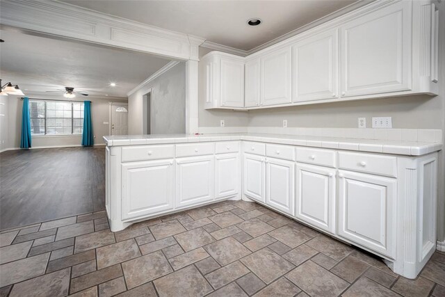 4505 N Peniel Ave, Bethany, OK 73008 - kitchen with tile counters, ceiling fan, white cabinets, open floor plan, and ornamental molding