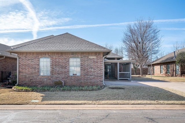 view of front of home featuring brick siding and roof with shingles