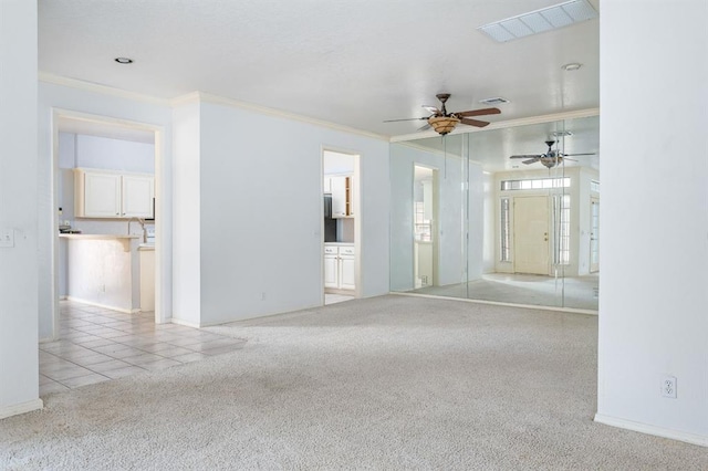spare room featuring visible vents, carpet, ceiling fan, and crown molding