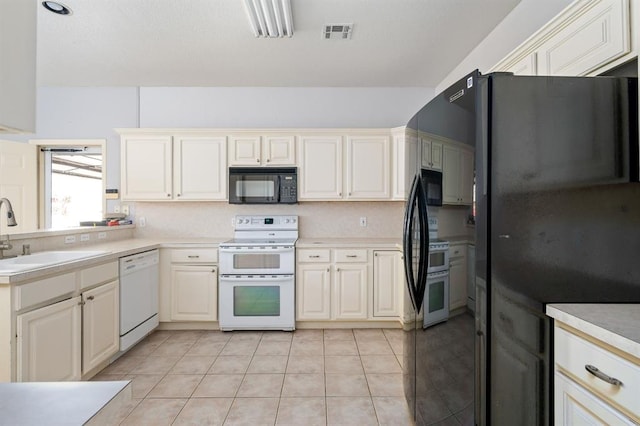 kitchen with visible vents, light countertops, light tile patterned floors, black appliances, and a sink