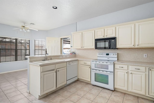 kitchen with white appliances, a peninsula, a sink, light countertops, and cream cabinets