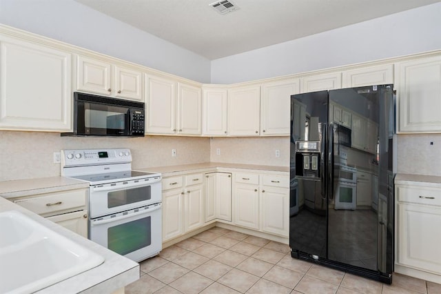 kitchen featuring visible vents, light countertops, light tile patterned flooring, cream cabinetry, and black appliances