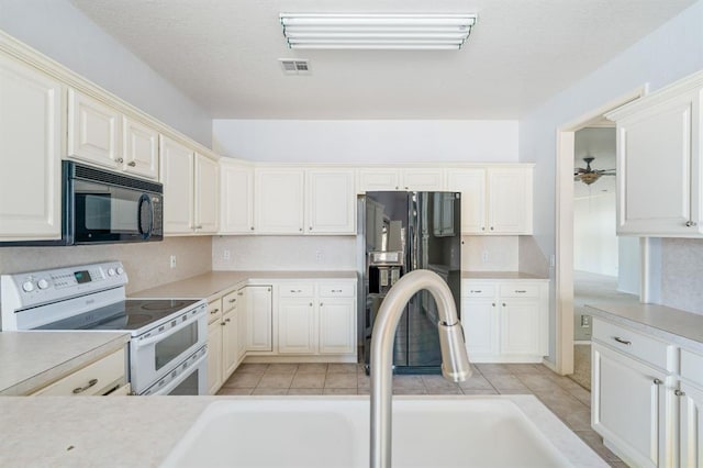 kitchen with visible vents, black appliances, decorative backsplash, and a sink
