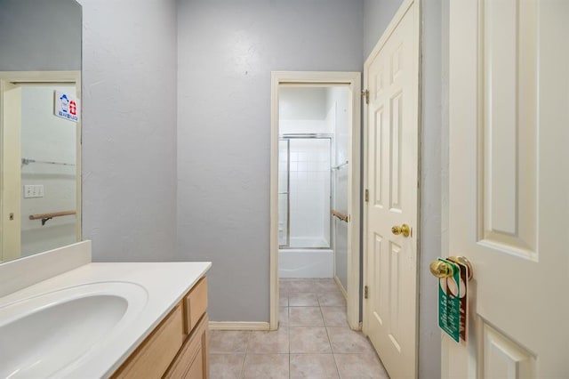 bathroom with tile patterned floors, enclosed tub / shower combo, baseboards, vanity, and a textured wall
