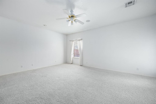 empty room with visible vents, light colored carpet, and a ceiling fan