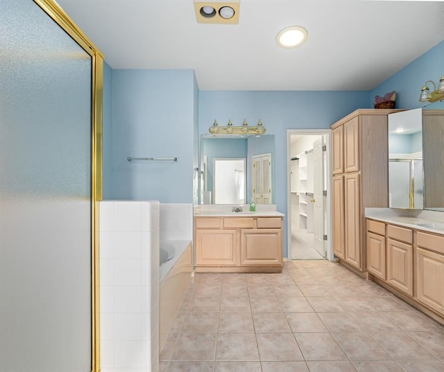 full bath with a garden tub, two vanities, a stall shower, tile patterned floors, and a sink