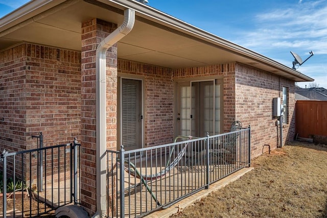 entrance to property featuring fence and brick siding