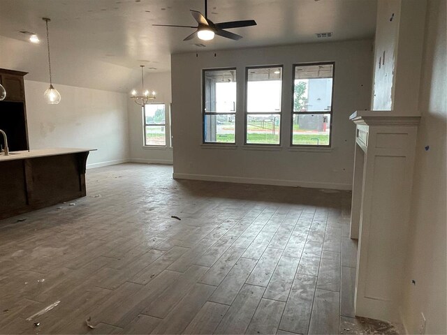 unfurnished living room with visible vents, lofted ceiling, baseboards, light wood-type flooring, and ceiling fan with notable chandelier