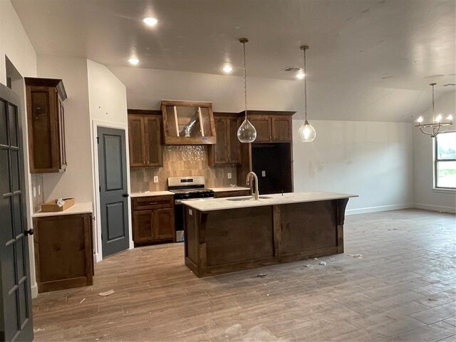 kitchen with light wood-style floors, a sink, decorative backsplash, and gas stove