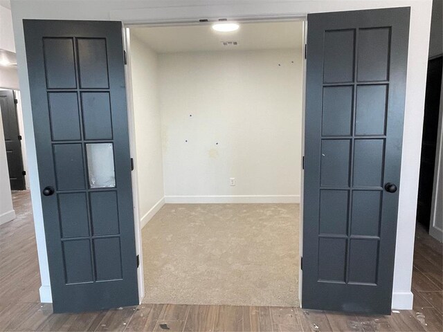 carpeted spare room with baseboards, wood finished floors, and visible vents