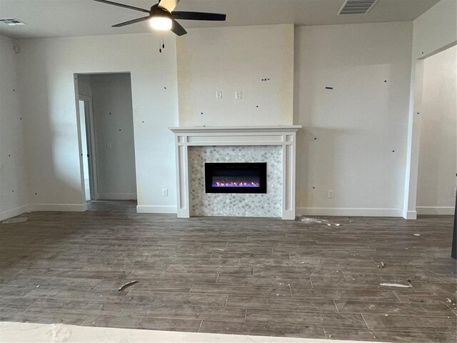 unfurnished living room with ceiling fan, visible vents, wood finished floors, and a high end fireplace