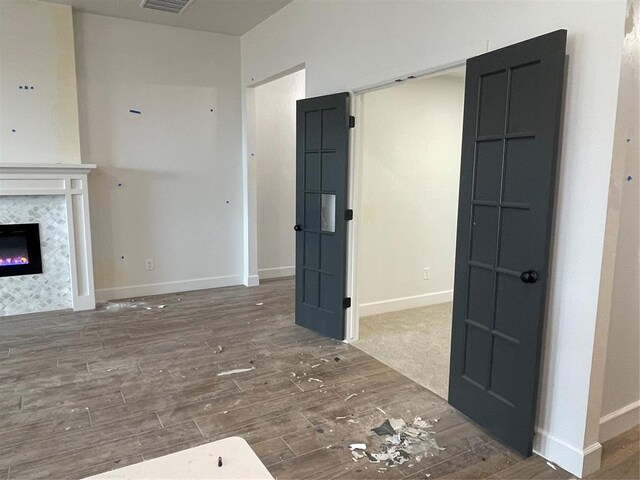 unfurnished living room with a glass covered fireplace, baseboards, wood finished floors, and visible vents