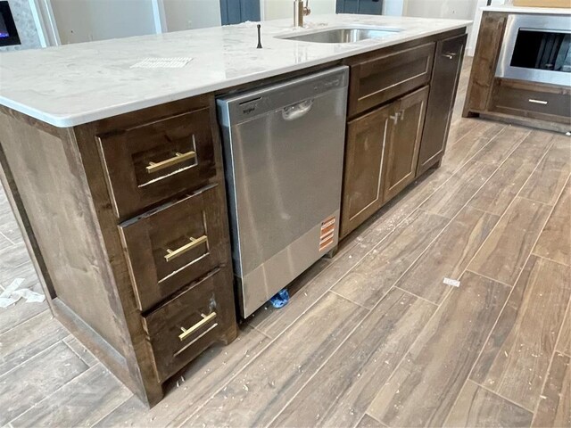 kitchen featuring dark brown cabinetry, light stone countertops, dishwasher, a sink, and light wood-style floors