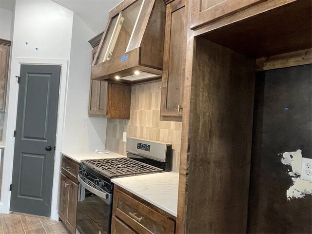 kitchen featuring stainless steel range with gas cooktop, wall chimney exhaust hood, and tasteful backsplash