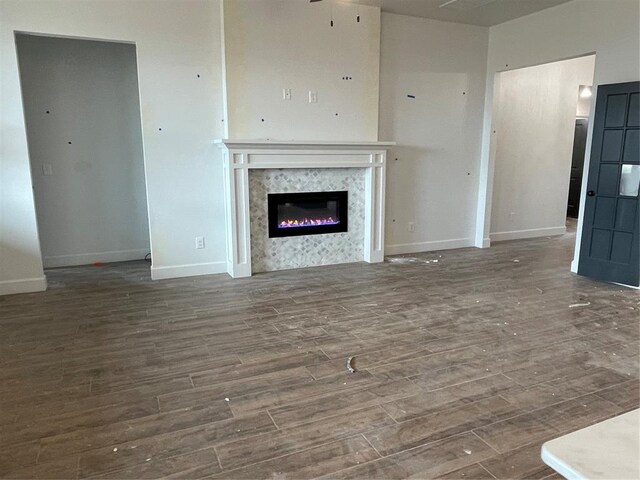 unfurnished living room with baseboards, wood finished floors, and a fireplace