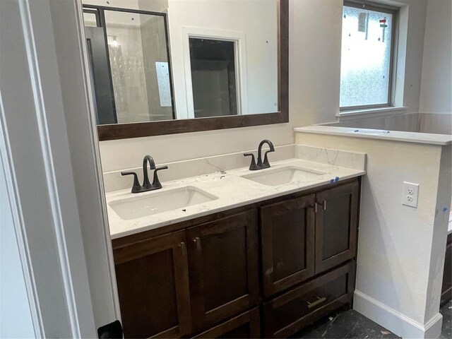 bathroom featuring a sink, baseboards, a shower stall, and double vanity