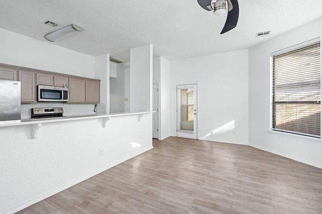 3833 Ives Way, Norman, OK 73072 - kitchen featuring stainless steel appliances, ceiling fan, a breakfast bar, light countertops, and light wood-style floors